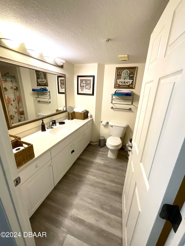 bathroom with toilet, vanity, a textured ceiling, and hardwood / wood-style flooring