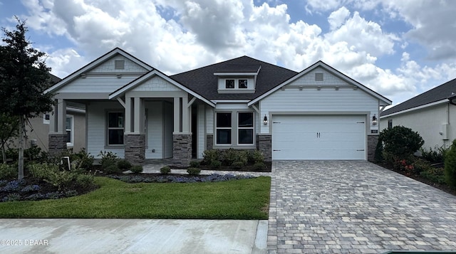 495 Stirling Bridge Dr, Ormond Beach, FL 32174 - craftsman-style house featuring decorative driveway, a garage, a front yard, stone siding, and a porch