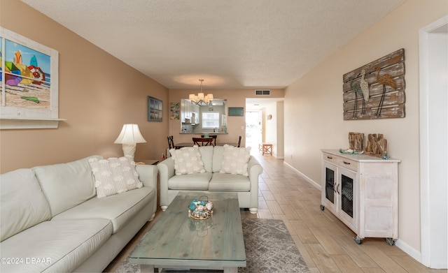 living room featuring light hardwood / wood-style floors, a chandelier, and a textured ceiling