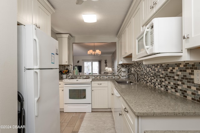 kitchen with hanging light fixtures, white appliances, sink, and white cabinets