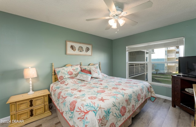 bedroom featuring ceiling fan, a textured ceiling, and light hardwood / wood-style floors