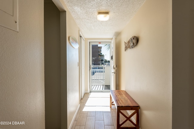 hall featuring a textured ceiling and light hardwood / wood-style flooring