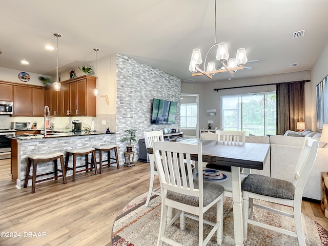 dining area featuring sink, an inviting chandelier, and light hardwood / wood-style flooring