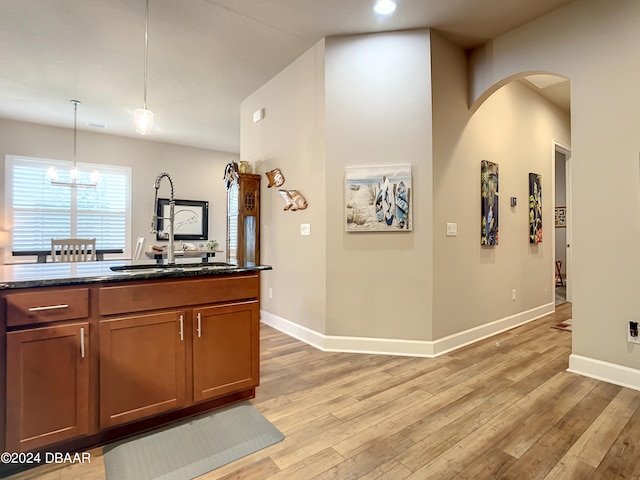 kitchen with pendant lighting, light wood-type flooring, a notable chandelier, and sink