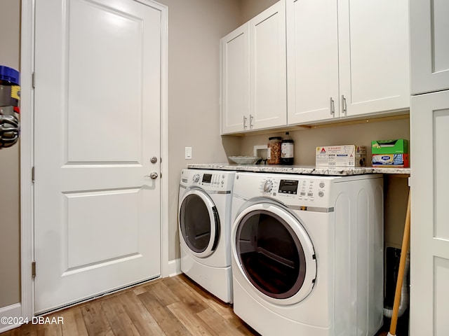 laundry room with light wood-type flooring, washer and clothes dryer, and cabinets