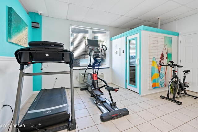 exercise room with a paneled ceiling and light tile patterned floors