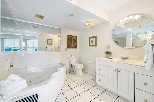 bathroom featuring toilet, tile patterned flooring, a textured ceiling, tiled bath, and vanity