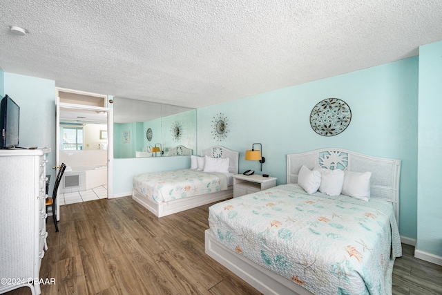 bedroom featuring ensuite bathroom, wood-type flooring, and a textured ceiling