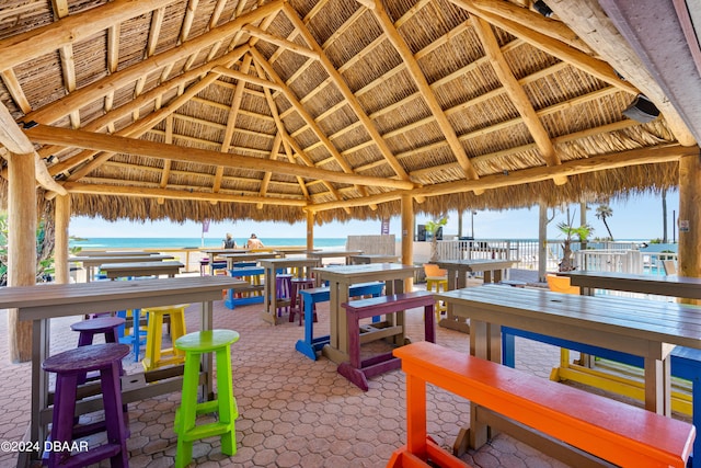 exterior space with an outdoor bar, a water view, a view of the beach, and a gazebo