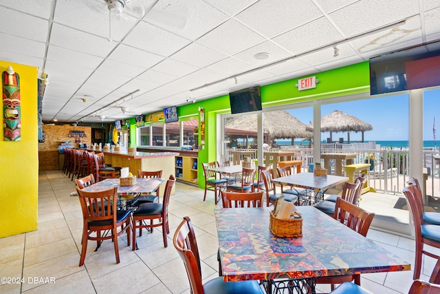 tiled dining space with a drop ceiling