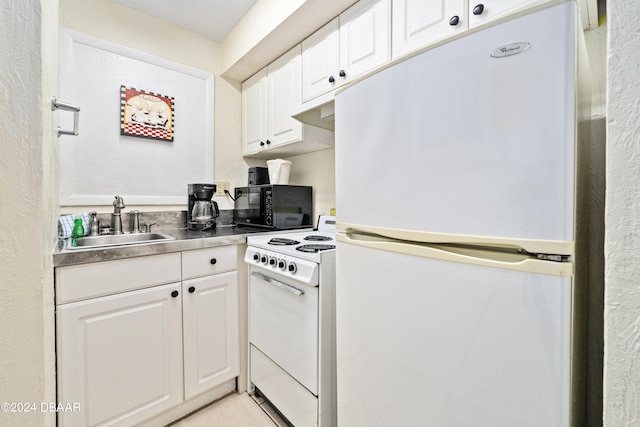 kitchen with white appliances, white cabinetry, sink, and stainless steel counters