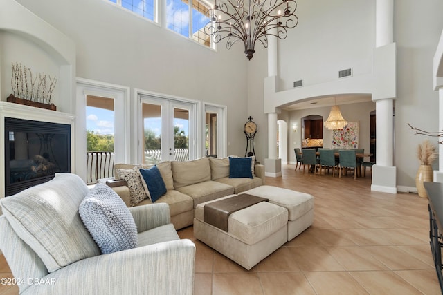 tiled living room with a chandelier, a high ceiling, and french doors