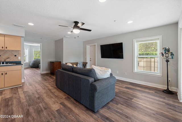 living room featuring a textured ceiling, dark hardwood / wood-style flooring, ceiling fan, and sink