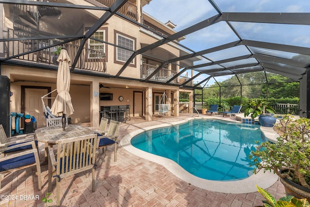 view of pool featuring glass enclosure, a patio area, and an outdoor bar