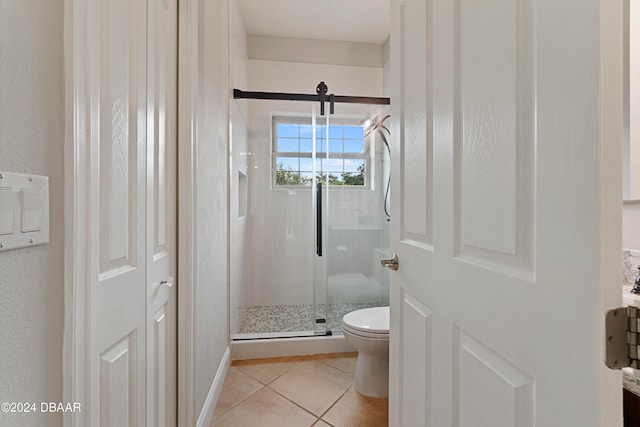 bathroom with tile patterned floors, a shower with door, and toilet