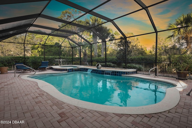 pool at dusk with glass enclosure, an in ground hot tub, and a patio