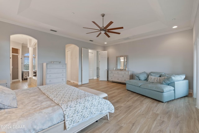 bedroom with light wood-type flooring, a tray ceiling, ceiling fan, and crown molding