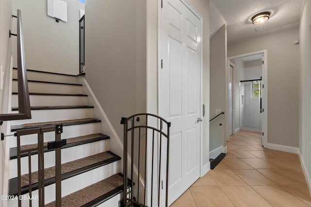 stairway featuring tile patterned floors and a textured ceiling