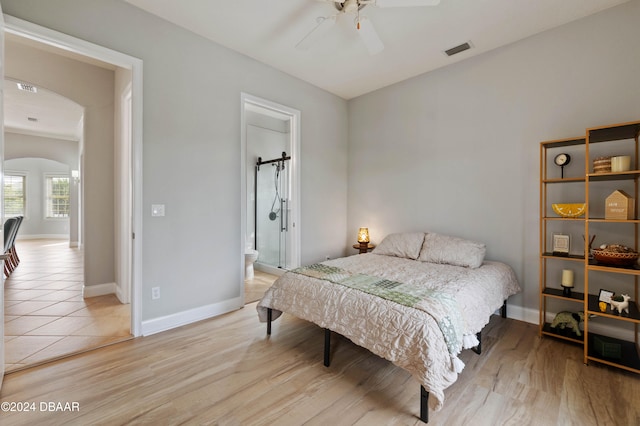 bedroom featuring light wood-type flooring, ceiling fan, and connected bathroom