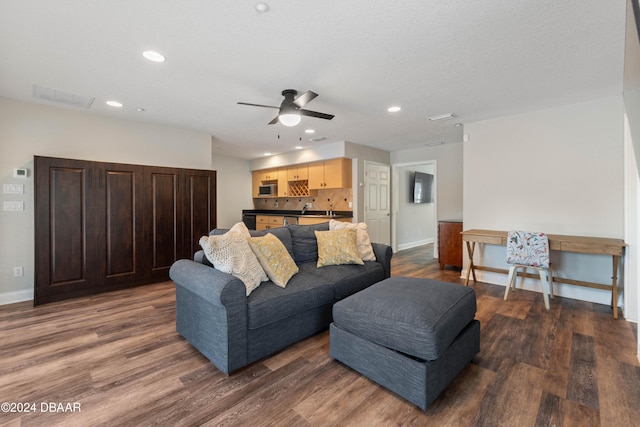 living room with ceiling fan and dark wood-type flooring