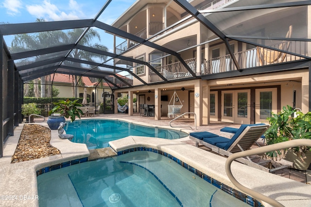 view of pool featuring glass enclosure, a patio area, and an in ground hot tub