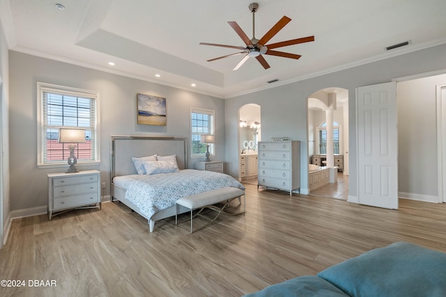 bedroom featuring ceiling fan, a raised ceiling, light wood-type flooring, and multiple windows