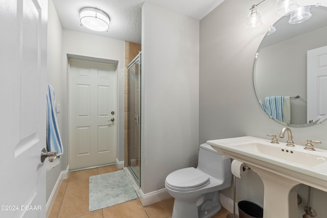 bathroom featuring tile patterned floors, toilet, a shower with shower door, and a textured ceiling