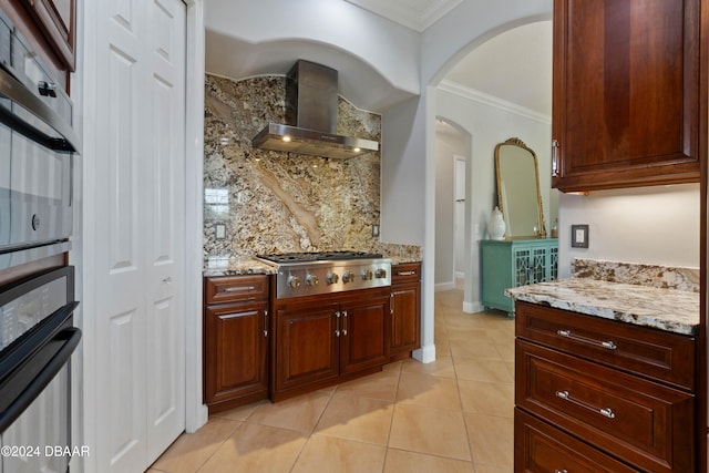 kitchen featuring light stone countertops, ornamental molding, wall chimney range hood, and stainless steel gas stovetop