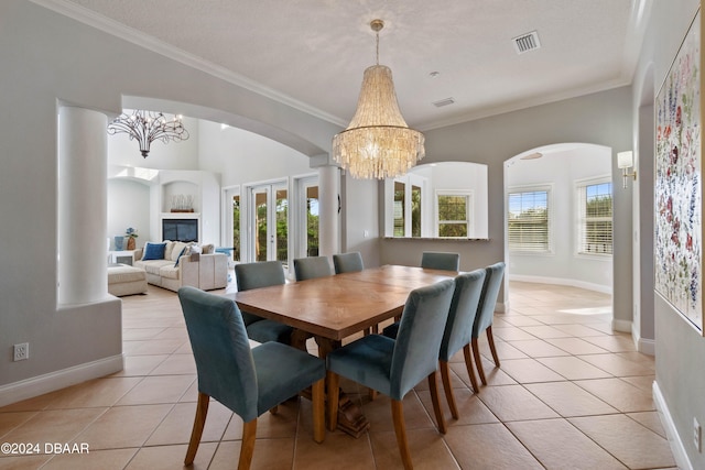 dining area with light tile patterned floors, a textured ceiling, an inviting chandelier, and ornamental molding