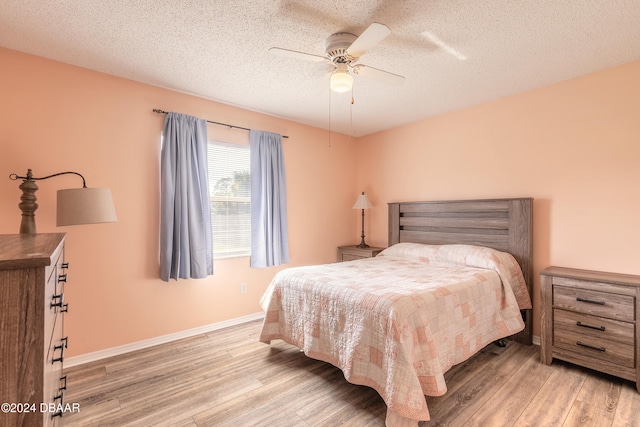 bedroom with ceiling fan, hardwood / wood-style floors, and a textured ceiling