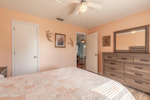 bedroom featuring hardwood / wood-style floors, a textured ceiling, and ceiling fan