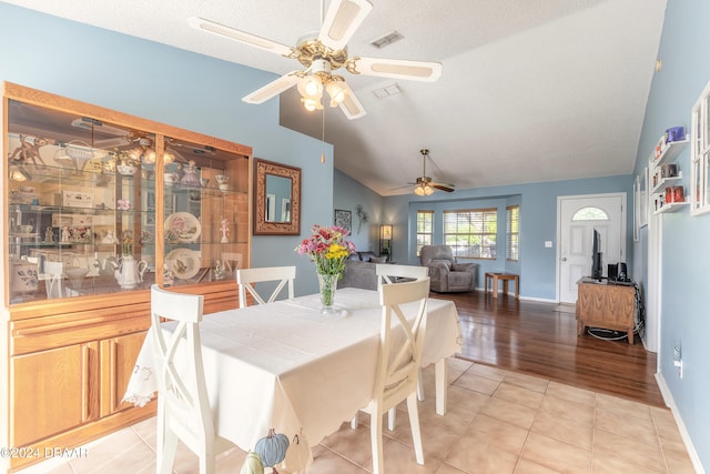 tiled dining area with vaulted ceiling, ceiling fan, and a textured ceiling