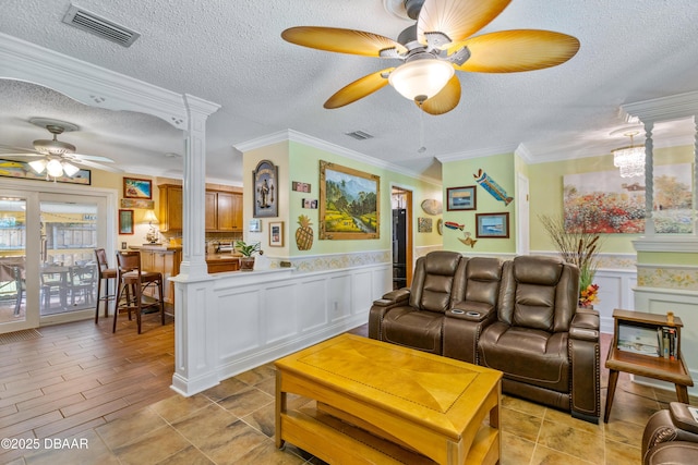 3048 Mango Tree Dr, Edgewater, FL 32141 - living room with a ceiling fan, ornate columns, a textured ceiling, a wainscoted wall, and a decorative wall