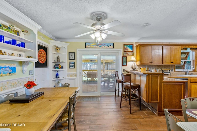 3048 Mango Tree Dr, Edgewater, FL 32141 - kitchen with a textured ceiling, brown cabinets, a ceiling fan, dark wood-type flooring, and a breakfast bar