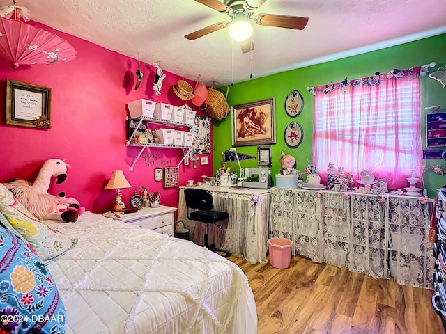 bedroom with hardwood / wood-style floors, ceiling fan, and a textured ceiling