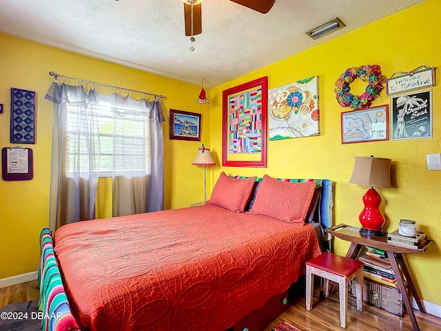 bedroom with ceiling fan, wood-type flooring, and a textured ceiling