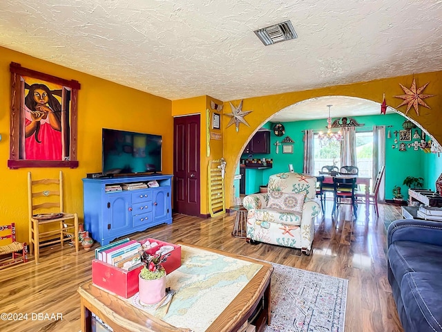 living room featuring hardwood / wood-style floors, a textured ceiling, and a chandelier