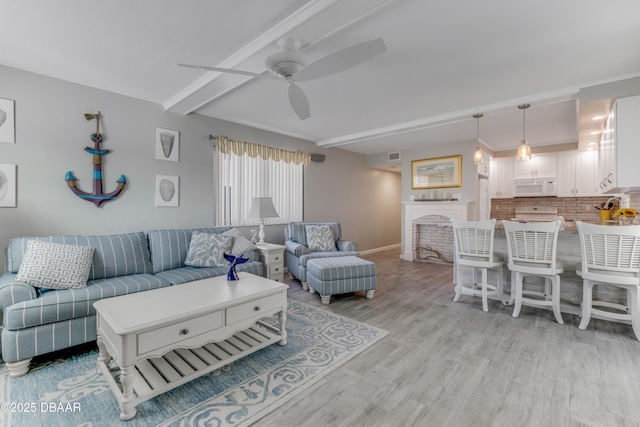 living room featuring ceiling fan, light hardwood / wood-style floors, and beam ceiling