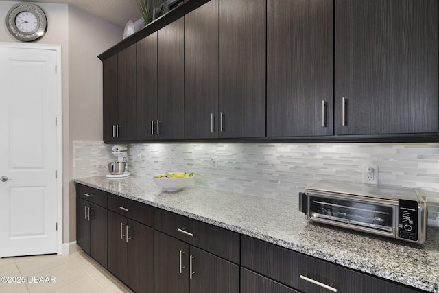 6279 W Fallsgrove Ln, Port Orange, FL 32128 - kitchen with light tile patterned flooring, tasteful backsplash, light stone countertops, and dark brown cabinetry
