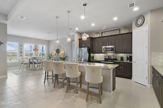 6279 W Fallsgrove Ln, Port Orange, FL 32128 - kitchen featuring appliances with stainless steel finishes, backsplash, a breakfast bar, a center island with sink, and dark brown cabinetry