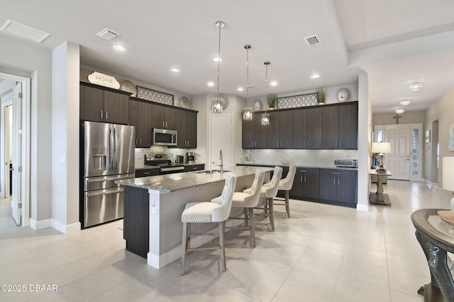 6279 W Fallsgrove Ln, Port Orange, FL 32128 - kitchen with stainless steel appliances, backsplash, a kitchen breakfast bar, a kitchen island with sink, and dark brown cabinetry