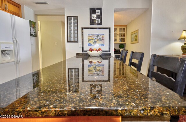 4435 S Atlantic Ave Unit 416, Ponce Inlet, FL 32127 - kitchen with white fridge with ice dispenser, dark stone countertops, and brown cabinets