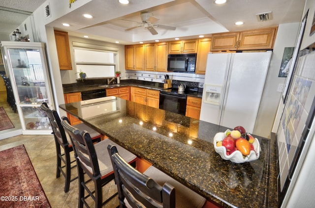 4435 S Atlantic Ave Unit 416, Ponce Inlet, FL 32127 - kitchen with black appliances, a raised ceiling, recessed lighting, a ceiling fan, and a kitchen bar