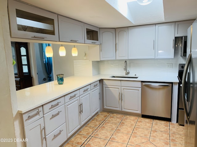 kitchen featuring sink, decorative backsplash, hanging light fixtures, stainless steel dishwasher, and kitchen peninsula