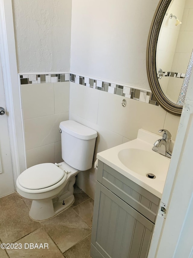 bathroom featuring vanity, tile walls, and toilet