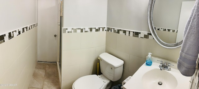 bathroom featuring toilet, sink, and tile walls