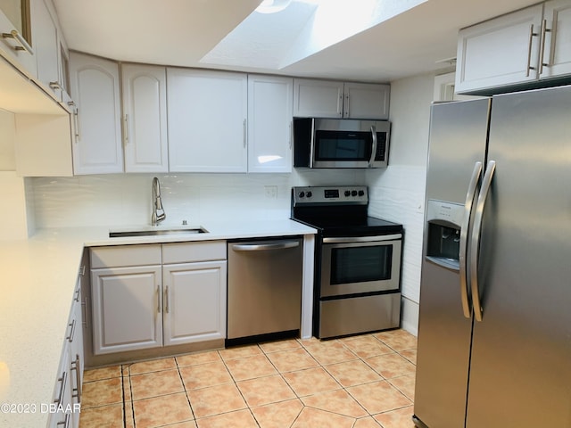 kitchen with sink, white cabinetry, backsplash, stainless steel appliances, and light tile patterned flooring