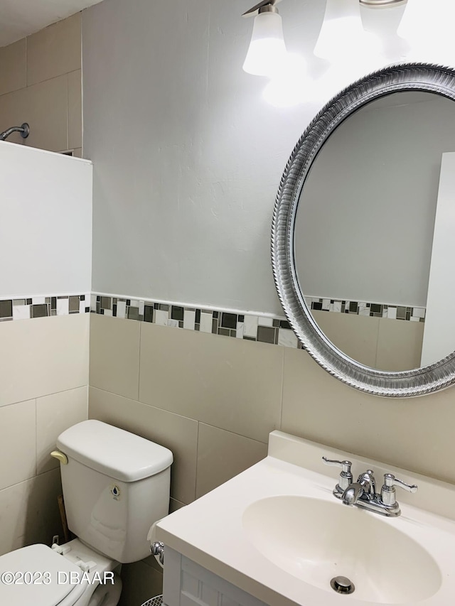 bathroom featuring tile walls, vanity, and toilet