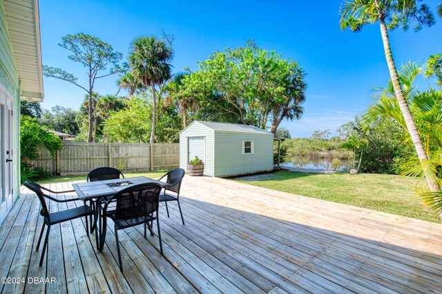 deck featuring a shed, a water view, and a yard