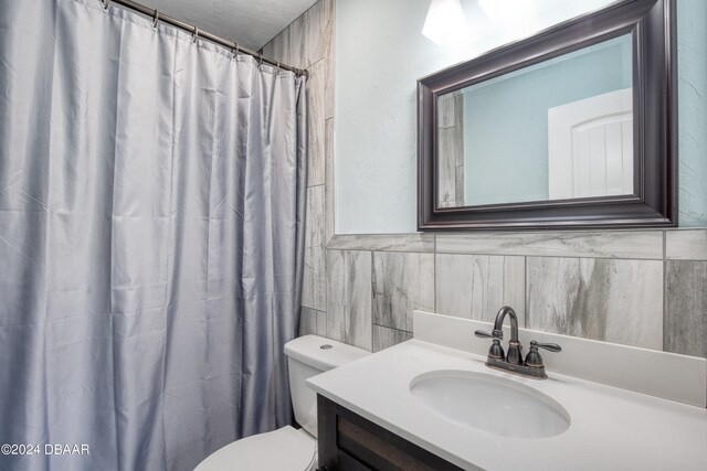 bathroom with tile walls, vanity, and toilet